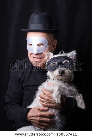 A senior pet owner and dog dressed alike in masks for Halloween.