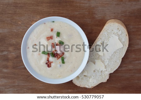 Bowl of creamy loaded potato soup with bacon bits and scallion on top.  Top down view.