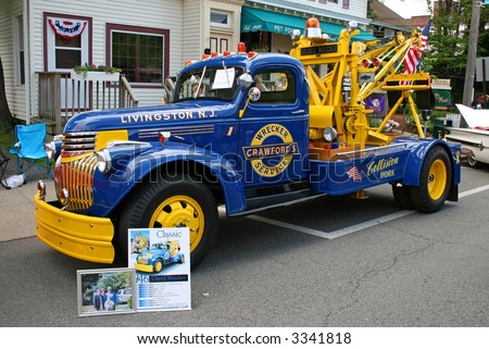 A tow truck displayed at a street antique car show