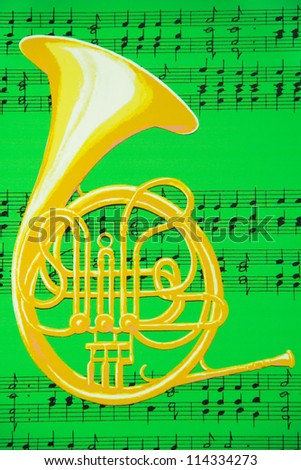 A brass French horn is against a background of music notes on a green sheet.