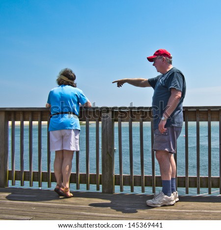A man and a woman watch for seals off the Chatham Fish Pier, MA, on Cape Cod.