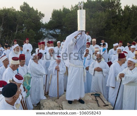 NABLUS, WEST BANK - JUNE 24 : A priest of the ancient Samaritan community holds up a Torah scroll during the holy day of Shavuot in Mount Gerizim on June 24 2012