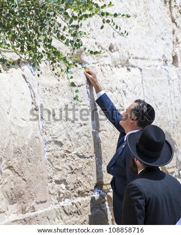 JERUSALEM - JULY 29 :  US Republican presidential candidate Mitt Romney places a mesage written on paper in the stones of the Western wall during his visit to  Jerusalem, Israel on July 29, 2012