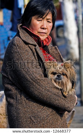 Chinese woman holding her dog in Shanghai street