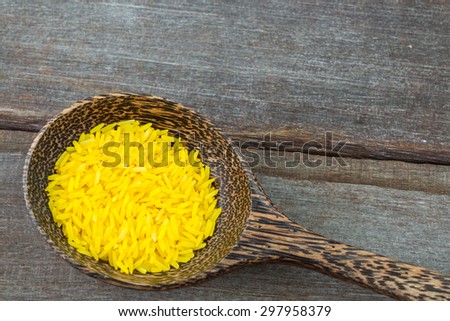 Color rice in wood spoon on wood background