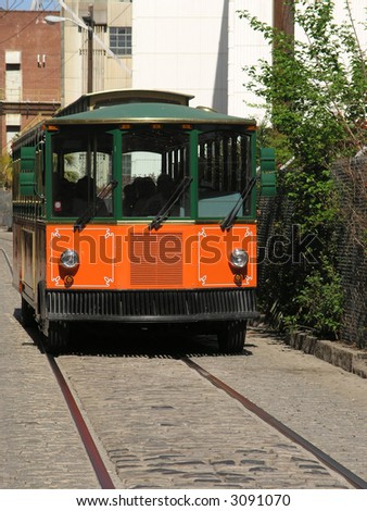 Orange and black Trolley Tour bus on cobblestone street