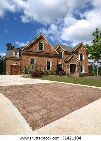 Luxury Model Home Exterior stone driveway with cloudy sky