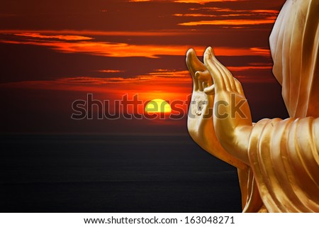 hand Buddha statue with sunset sky background hand Buddha statue with sunset sky background