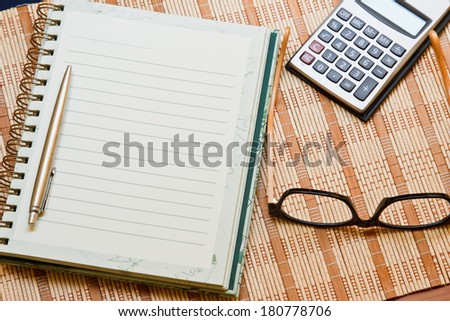 Calculator with notebook & pen on bamboo wooden background