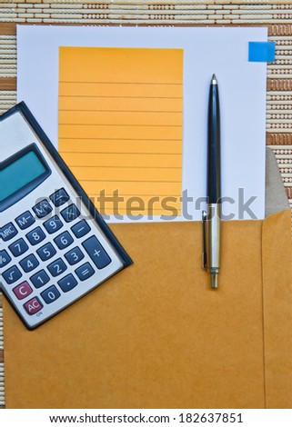 Calculator with paper & pen on bamboo wooden background