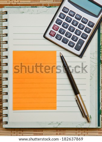 Calculator with notebook & pen on bamboo wooden background