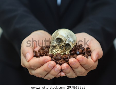 Senior woman holding human skull in coffee beans.
