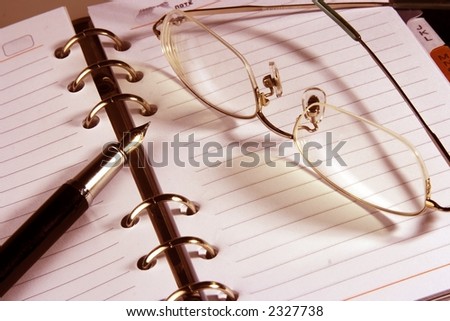 Address book with eyeglasses and fountain pen in warm color.