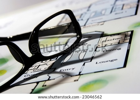 An architecture blueprint with black frame eyeglasses on top.