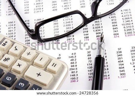 Financial statement with calculator, eyeglasses and fountain pen.