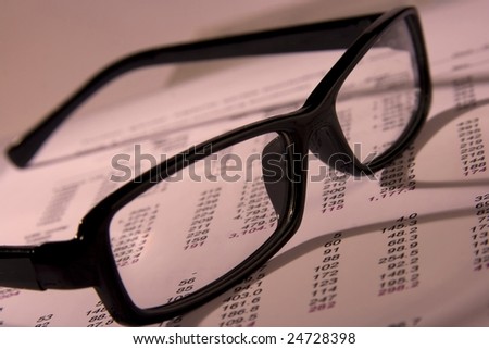 A Financial statement with a black frame eyeglasses.
