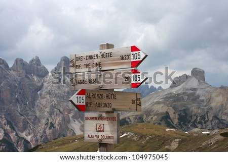 Alpine hiking trails hint along a trail, on background high rocky mountains, Italy