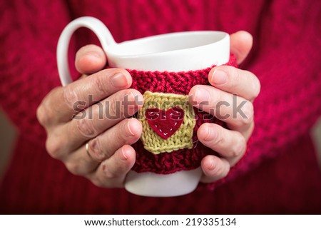 Knitted woolen cups in female hands