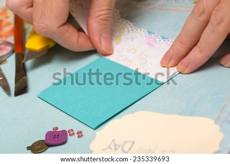 scrapbook background. Card and tools with decoration. Hands