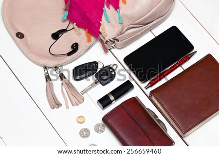 the contents of the female handbag - wallet, keys, phone, lipstick, perfume