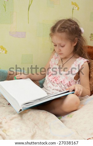 little child girl sitting on a bed and looking at the empty page of the book
