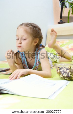 little girl turning over the pages of magazines lying on the parents` bed