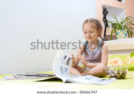 little girl turning over the pages of magazines sitting on the parents` bed