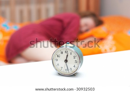 alarm clock disturbing a sleeping woman that is defocused