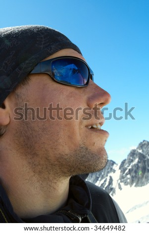 hiker high at the mountains looks at the ultimate aim of his trip. It is reflected at his glasses