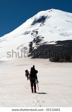 climbers walking up by the snowed glacier to the high summit