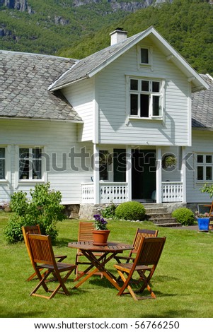 traditional norwegian wooden house standing on a lawn and mountains in the background