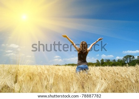young girl joys on the wheat field at the bright sunny day