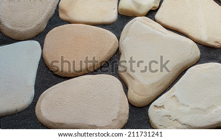 Plain spa stones on the dark black sand. Natural background.