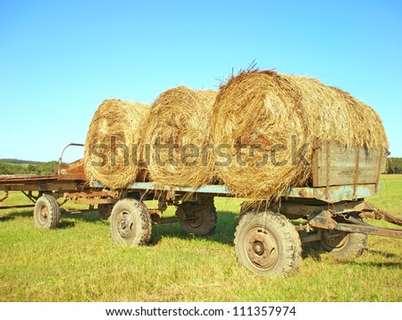 Three rolls of hay on a cart in the field
