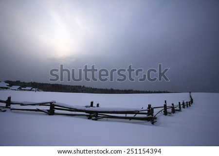 The fence of the village in a snowy forest. Russia