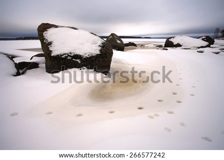 Winter landscape with rocks, lake and forest