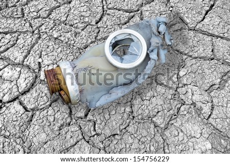 Dirty broken gas mask on cracks, symbolizing the 