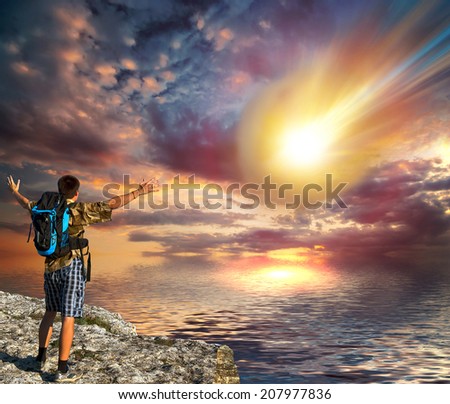 A young man with a backpack looks like a huge fiery meteorite falls into the sea