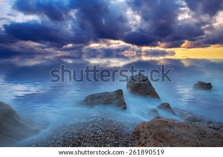 Dramatic sea sunset. Storm clouds over the stony shore. natural composition