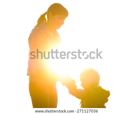 Young mother and son holding hands and laughing on the background of the backlight. family composition