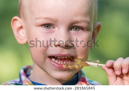 Little boy eating candy on a stick. Family composition
