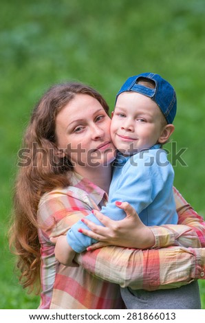Mother and her son hugging in the street and look right. Family composition