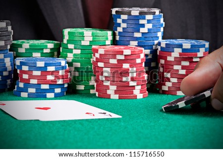 A man playing poker and raising his bet with two black chips