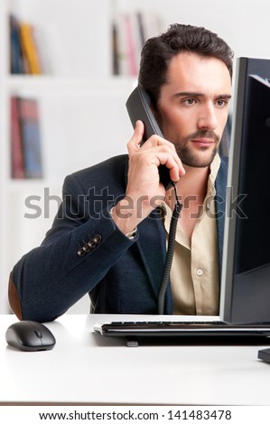 Man looking at a computer screen, on the phone, thinking about the job at hand