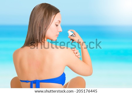 Woman applying sunscreen on her arm, in a beach