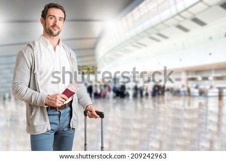 Man waiting at an airport, holding tickets, in an airport
