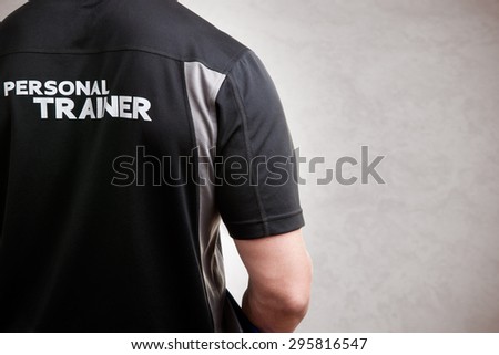 Personal Trainer, with his back facing the camera, in a grey background
