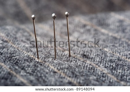 Closeup of three pins on a grey striped suit