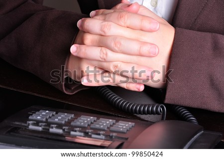 Businessperson with hands crossed waiting for the phone to ring