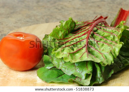 Red chard leaves and tomato on a cutting board